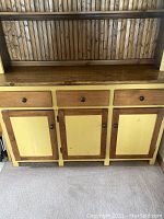 Front view of custom buffet showing three drawers and three doors with yellow painted panels and natural wood top.