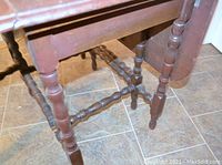 Turned wood legs and crossbars detail showing vintage craftsmanship and connection supports.