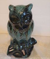 Front view of the blue-green glazed owl figurine with visible detailed facial features and perched on a stylized base.