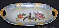 Oval luster dish with floral and bird design, ornate rim and handles, shown from top
