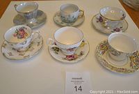 Top view of six assorted vintage china tea cups with matching saucers, showing diverse floral patterns and gold trim