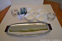 Photo showing two clear glasses with gold leaf design, four blue floral glasses, four white bowls with gold pattern and two Corelle cups with gold butterfly pattern on chrome tray with bakelite handles and feet