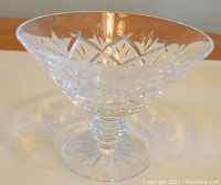 Close-up of a footed compote-style bowl with clear crystal and etched star and leaf cut patterns on the bowl surface and stem base.