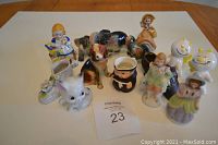 Lot of 11 assorted vintage figurines grouped on a white surface.