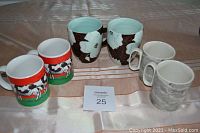 Three sets of coffee mugs on a tablecloth, showing all six mugs grouped in threes