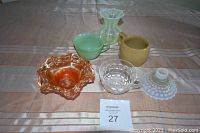 Photo of assorted vintage glassware items including decorative bowls and creamers on a table.
