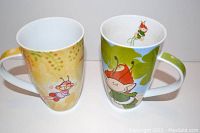 Front view of two mugs showing their colorful character designs and handles.