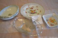 All four glassware items displayed on a wooden surface: clear glass bowl with silver overlay, oval footed dish, round floral plate with reticulated edges, small square floral dish with reticulated edges