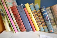 Side view of assorted vintage books showing titles, including children's and adult books.