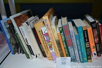 Side view of book spines showing a mixture of titles including Raising Dairy Goats, Riding the Tiger, Saint Joan, and others.