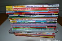 Stack of colorful teacher resource books on literacy, showing titles and grade levels on the spines such as Take it to Your Seat Literacy Centers, Read and Understand, Creative Writing Prompts, Poetry, and Values in Literature.