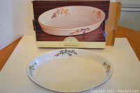 Close up of Woodhill oval stoneware baker with decorative floral design and original box showing the product name