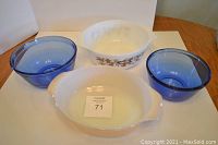 Four bowls: two blue glass mixing bowls, Pyrex England white casserole with floral pattern, and Fire King white oval casserole