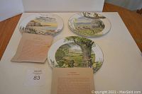 Three Royal Worcester collector plates arranged on white surface, accompanied by informational pamphlets.