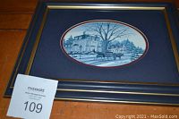 Photo of the framed print titled 'The Homecoming' showing a historic house and tree in blue tones with a gold-trimmed blue frame.