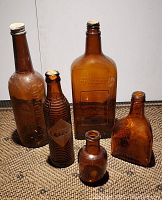 Front view of all five amber glass bottles on carpeted surface.