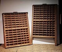 Two vintage printers drawers standing side by side with multiple small compartments each, showing overall structure and layout.