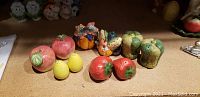Five sets of vintage salt and pepper shakers, front view showing apples, lemons, vegetables, strawberries, and bell peppers