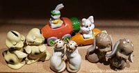 Front view of five sets of vintage ceramic salt and pepper shakers including animal and vegetable shapes on a wooden surface.