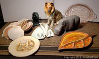 Photo showing front view of the lot including tiger and hippo figurines, shell dishes, decorative plates, and wooden trays.