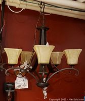 Photo of two dark metal hanging lamps with beige marbled glass shades against a red wall and ceiling pipes, showing overall condition and missing glass shade on one lamp