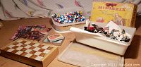 Overview of all items in the lot including bins with figurines, Minibrix box, wooden board games, comics, and playing cards