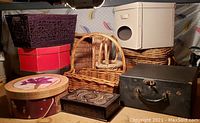 Overview of 11 assorted baskets, hat boxes, and cases showing their colors, shapes, and materials.