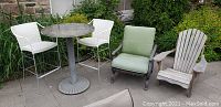 Full view of outdoor furniture set including round table with steel base and four chairs in a garden area.