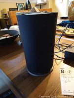Front view of the black cylindrical OnHub wireless router on a table showing its height and general shape.