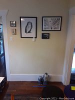 Wall with five framed art pieces: three unsigned, two signed, featuring an owl drawing, abstract piece, small photo, and colorful artworks.