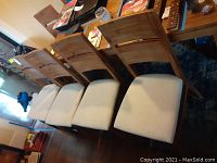 Six wooden dining chairs lined up showing backrests and seats