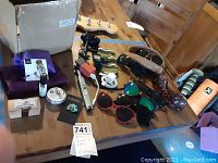 Overview of all items on wooden table showing sunglasses, cables, watch and lighter