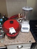 Full view of the red cast iron roasting pot, KitchenAid blender, wooden cutlery block, and knives on kitchen countertop.
