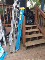 Two aluminum ladders leaning against deck rails, one blue Werner and one silver Gorilla