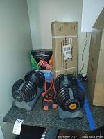 Two Nautilus adjustable dumbbells on gray plastic stand with orange resistance tubes and boxed balance balls behind