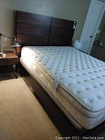 Side view of queen bed with Saatva mattress and dark wood headboard