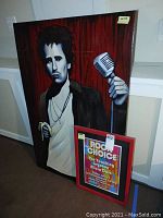 Framed painting on wood of a man holding a vintage microphone in dark tones with red and black background.