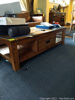 Solid oak coffee table from a side angle showing the solid wood construction and lower shelf storage.