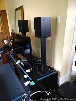 Polk Audio surround sound system speakers, including two satellite speakers on stands and a subwoofer, all black.