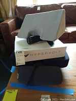 Overall lot view showing Hypervolt device mounted in foam insert on top of original box with black carrying case beneath