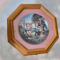 Photo of the porcelain collector plate mounted in the wooden octagon frame with pink fabric backing, showing the full lot from the front.
