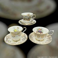 Photo of three Paragon footed teacups with matching saucers shown together, each cup decorated with different floral patterns and gold trim.