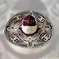 Top view of a burgundy Pigalle sombrero with elaborate silver embroidery and braided silver trim, displaying its wide brim and decorative motifs.