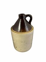 Front side view of the two-toned vintage ceramic crock showing the dark brown upper section and the natural beige lower body with texture.