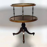 Full front view of the vintage Duncan Phyfe two-tiered round table on three legs with casters.
