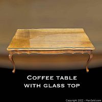 Vintage provincial style wooden coffee table with glass top, scalloped edges, shown from above with reflection on the glass.