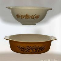 Two vintage Pyrex bowls displayed with one stacked over the other, showing the Butterfly Gold floral patterned bowl on top and the Old Orchard dish below with fruit designs.
