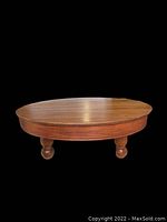 Front view of the vintage round wooden coffee table, showing round top and four round ball legs