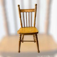 Front view of vintage Roxton child's wooden chair highlighting spindle back and wood finish.