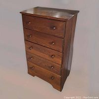 Front view of the vintage wooden chest of drawers showing all five drawers with round wooden knobs and the dark wood finish.